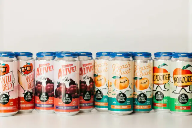 Assorted colorful canned beverages are lined up against a white background.