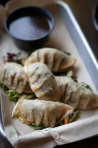 Shitaki Fried Dumplings on tray with sauce.