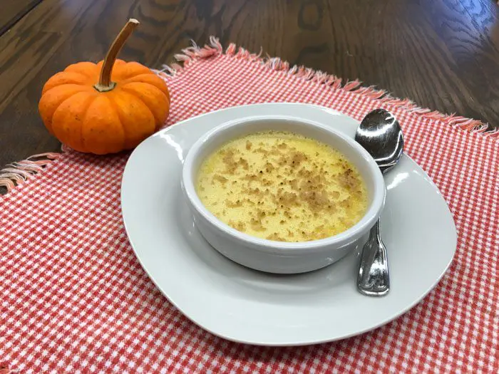 Eckert's Pie Pumpkin Creme Brûlée served in a bowl with red checked cloth and mini pumpkin.