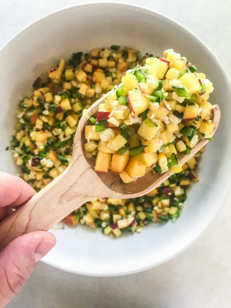 Scoop of Peach and Corn Salsa in white bowl.