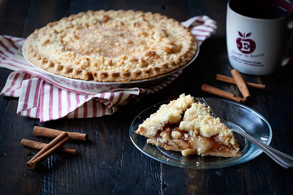 Whole Dutch apple pie and one pie slice served with coffee.