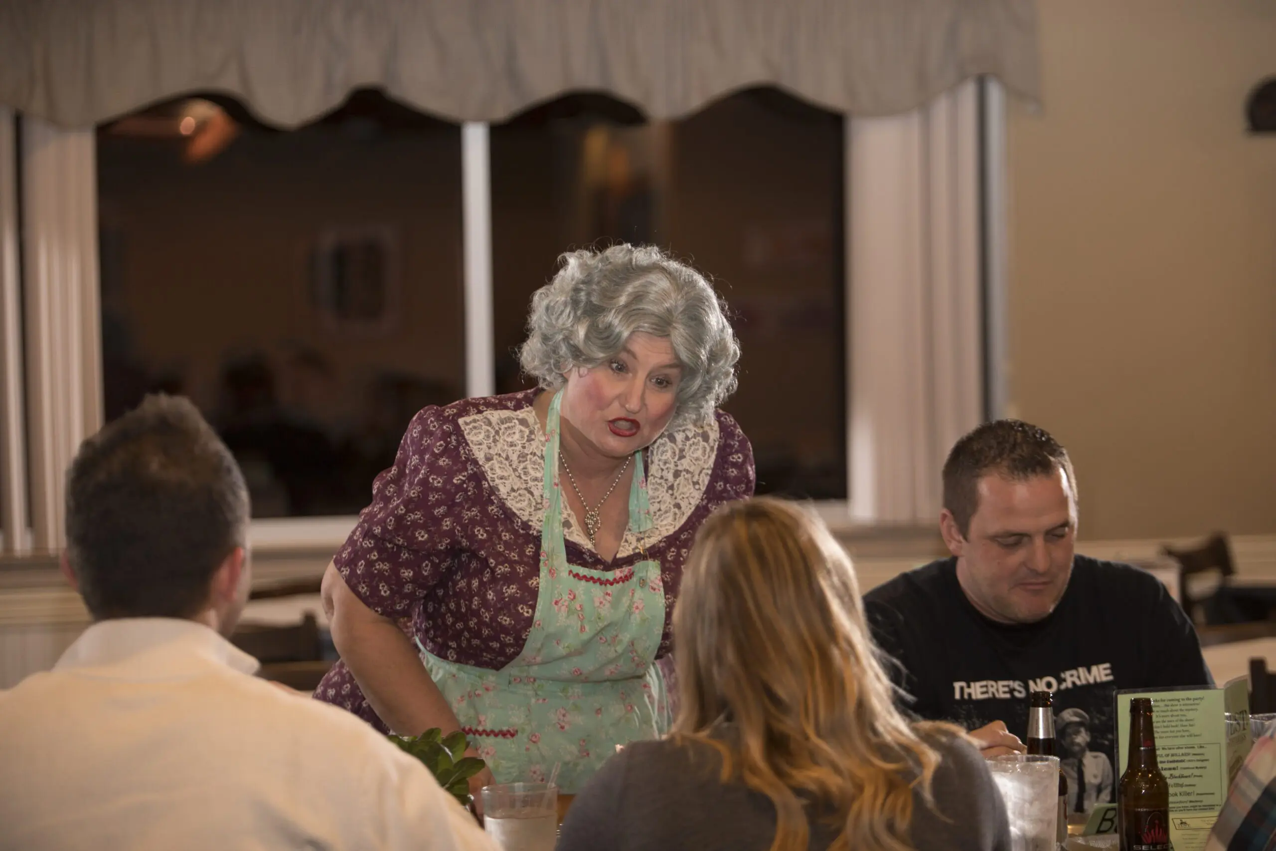 Murder Mystery Dinner close up of performer dressed in grey wig and apron.