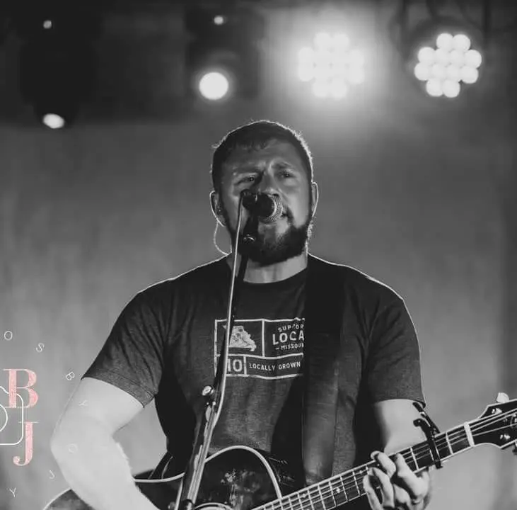 Cider Shed Live Music; Dustin Coleman B& W with guitar on stage.