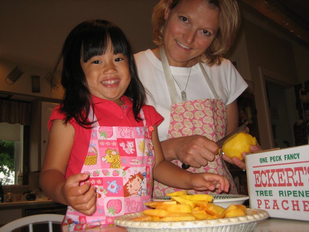 A picture of a woman and girl making grandma Eckert's peach custard pie