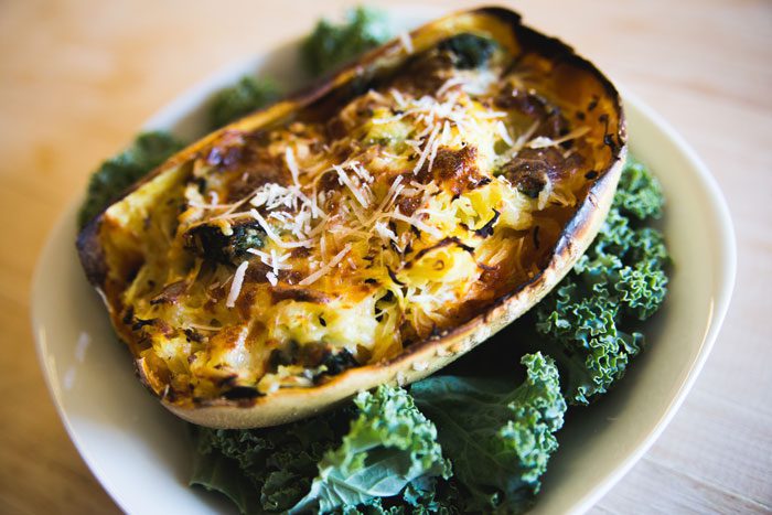 A picture of basked spaghetti squash lasagna on a bed of kale leaves